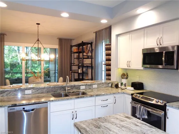 a kitchen with granite countertop a sink a counter space appliances and cabinets