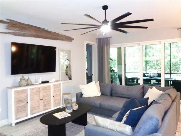 a living room with furniture a flat screen tv and a large window