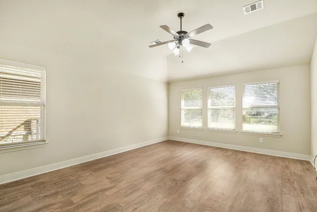 a view of an empty room with a window and wooden floor