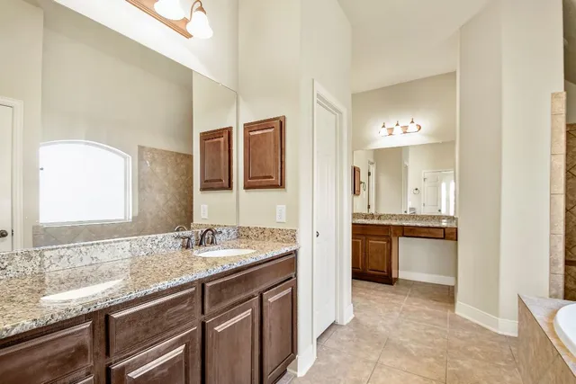 a spacious bathroom with a granite countertop sink and a mirror