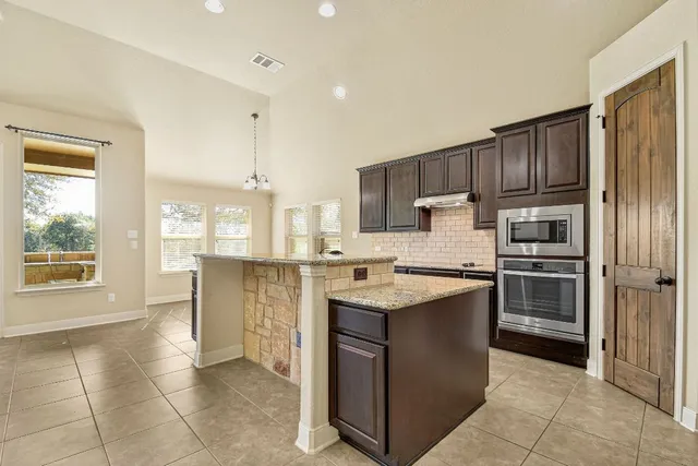 a kitchen with kitchen island granite countertop a stove sink and refrigerator