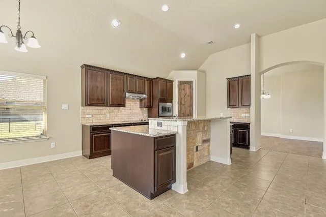 a kitchen with granite countertop a stove top oven and refrigerator