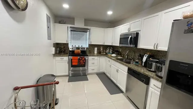 a kitchen with stainless steel appliances granite countertop a sink stove refrigerator and cabinets