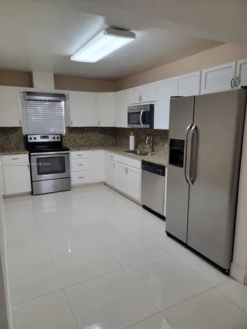a kitchen with stainless steel appliances granite countertop a refrigerator and a stove top oven