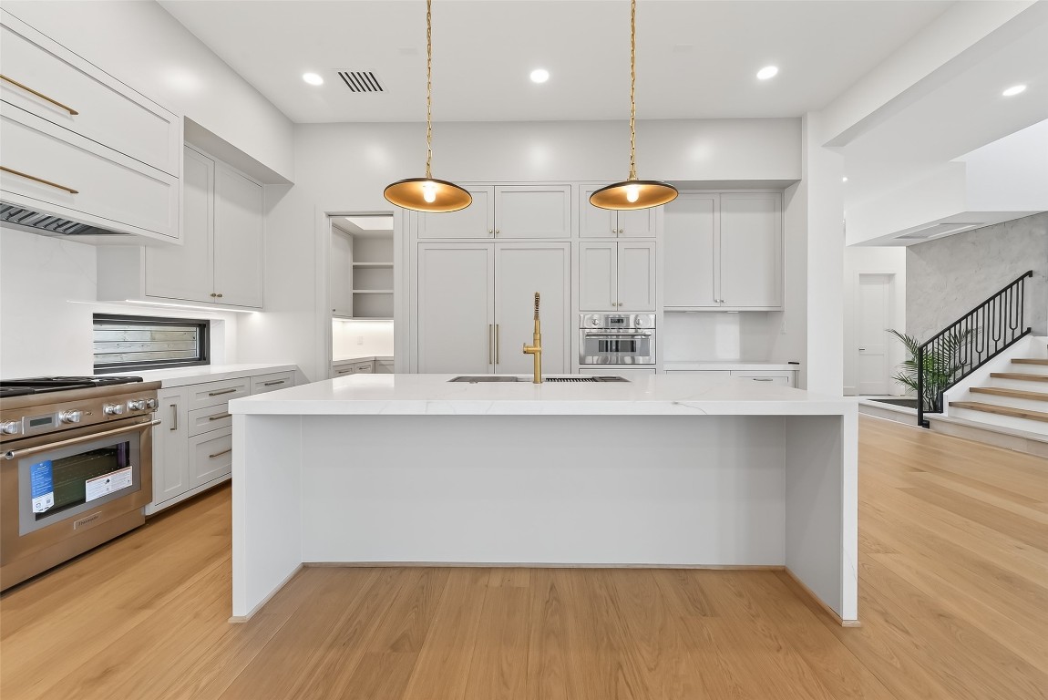6534 Corbin Street Houston, TX 77055 - Photo 18 of 50 a large kitchen with stainless steel appliances a large counter top a stove and a wooden floor