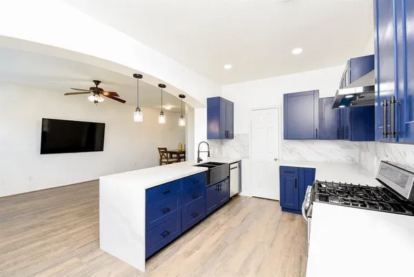a large kitchen with stainless steel appliances a stove a sink dishwasher and a refrigerator with wooden floor
