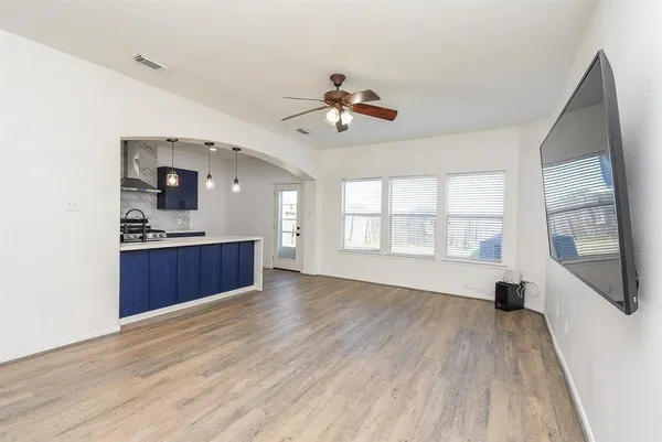 a view of kitchen and empty room with wooden floor and fan