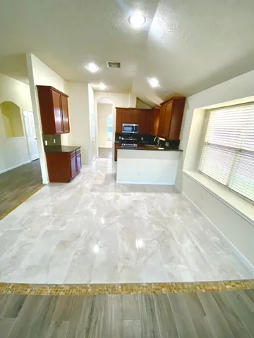 a view of a kitchen with kitchen island a sink wooden floor and a counter top space
