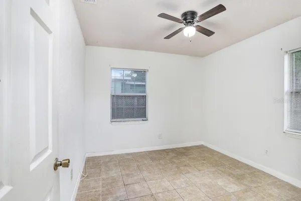 an empty room with windows and fan