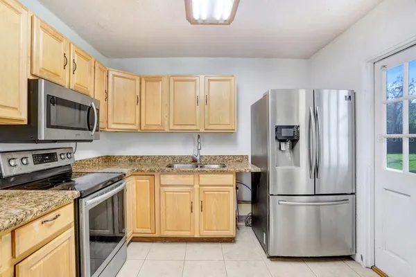 a kitchen with stainless steel appliances granite countertop a refrigerator stove a sink and dishwasher with wooden floor