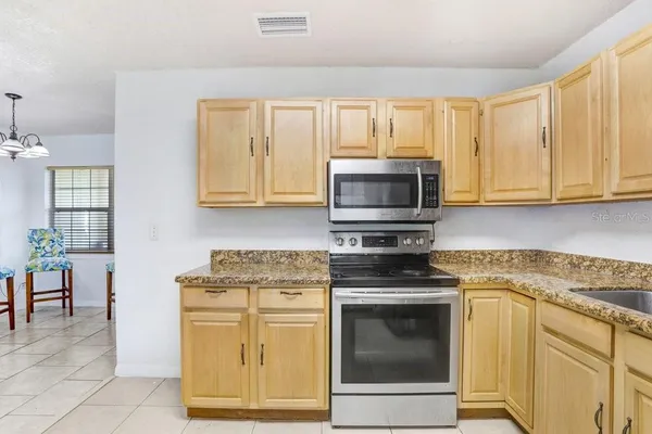 a kitchen with granite countertop white cabinets stainless steel appliances and a window