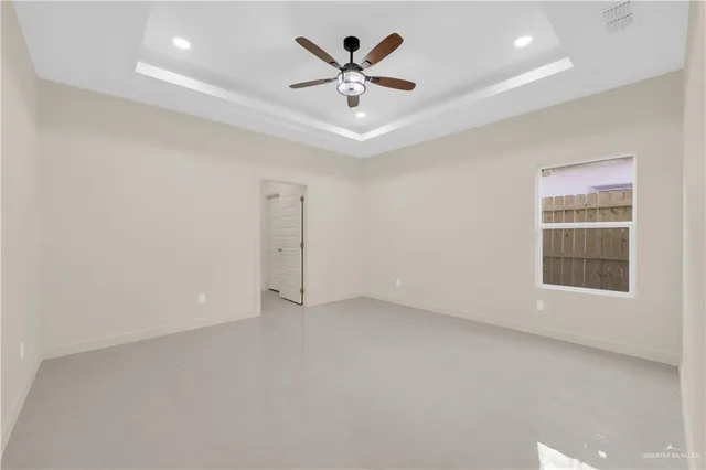 an empty room with windows and ceiling fan