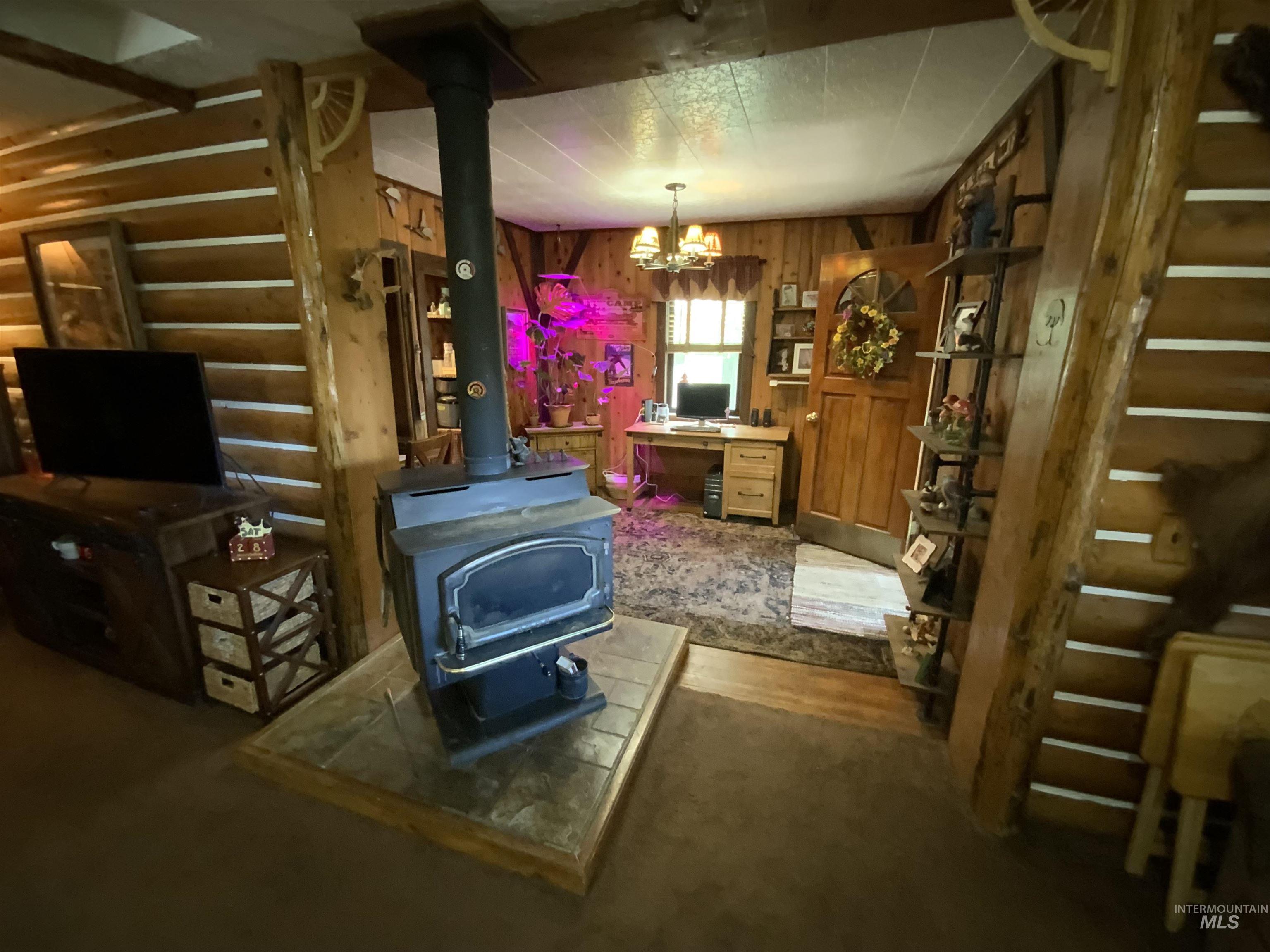 205 Alturas Avenue East Fairfield, ID 83327 - Photo 20 of 39 Living room with a wood stove, a chandelier, and wooden walls