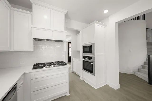 a kitchen with white cabinets and appliances