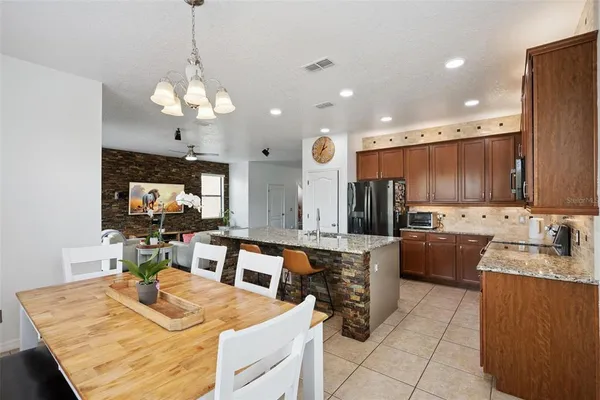a kitchen with stainless steel appliances granite countertop a sink counter space and chairs
