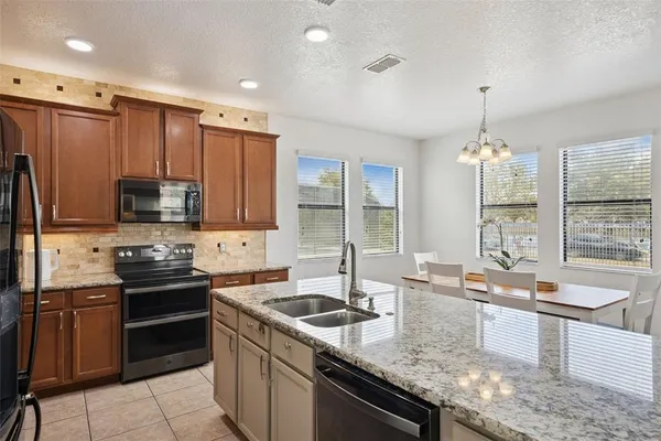 a kitchen with granite countertop stainless steel appliances cabinets a sink and a large window