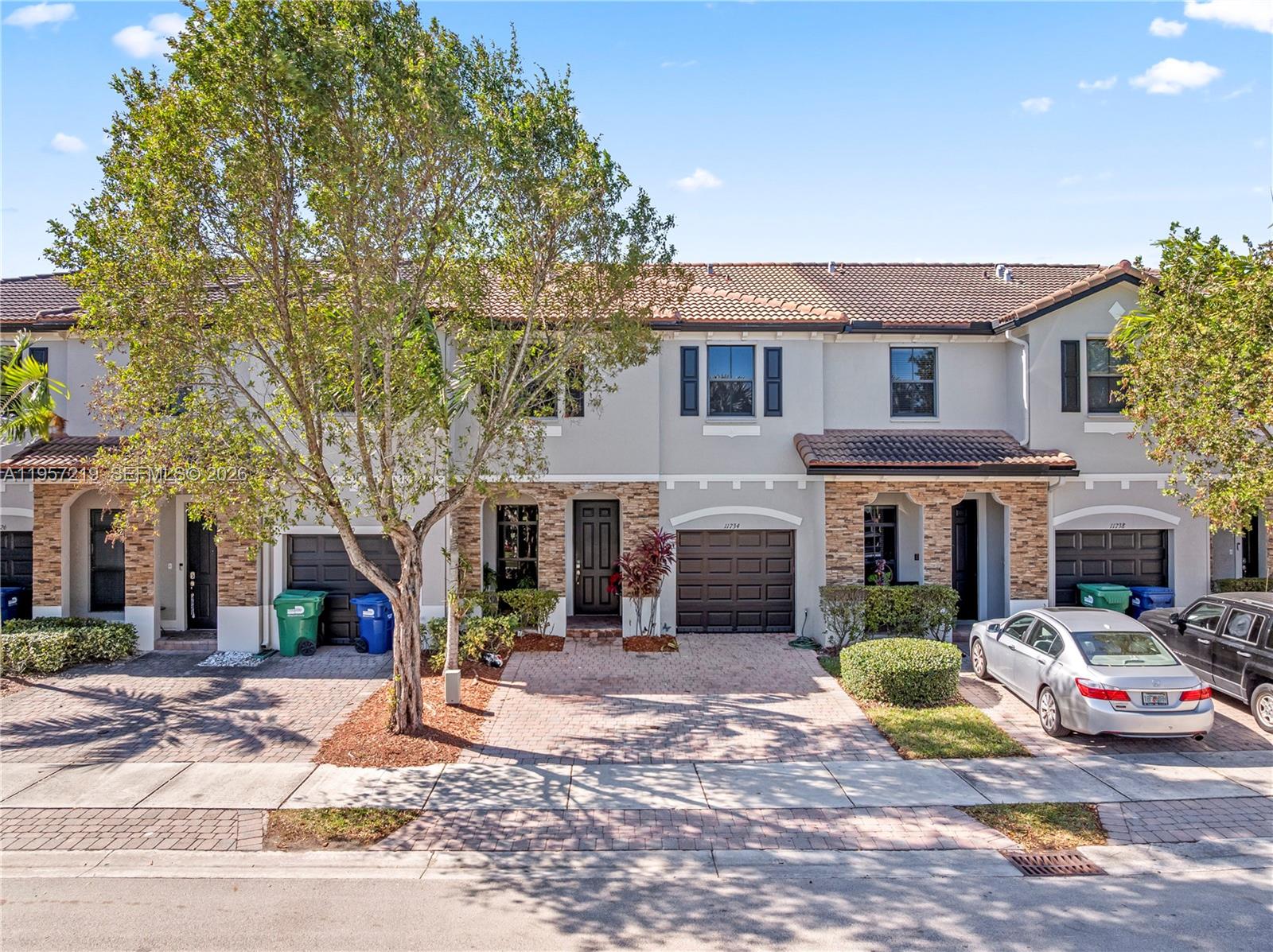 a view of a white house with a small yard and large tree