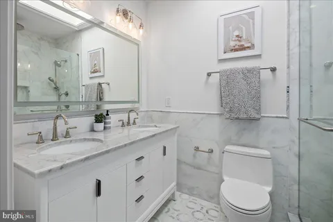 a bathroom with a granite countertop toilet sink and mirror