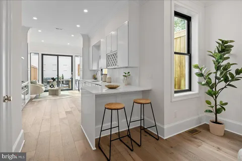 a room with stainless steel appliances a table chairs refrigerator and a window