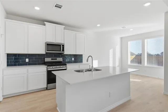 a kitchen with sink a microwave and cabinets