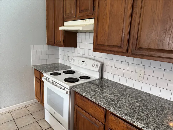 a kitchen with granite countertop a sink a stove and cabinets