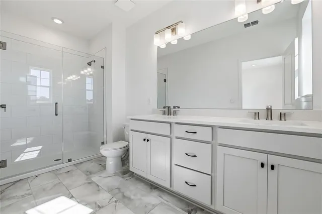 a bathroom with a double vanity sink toilet and shower