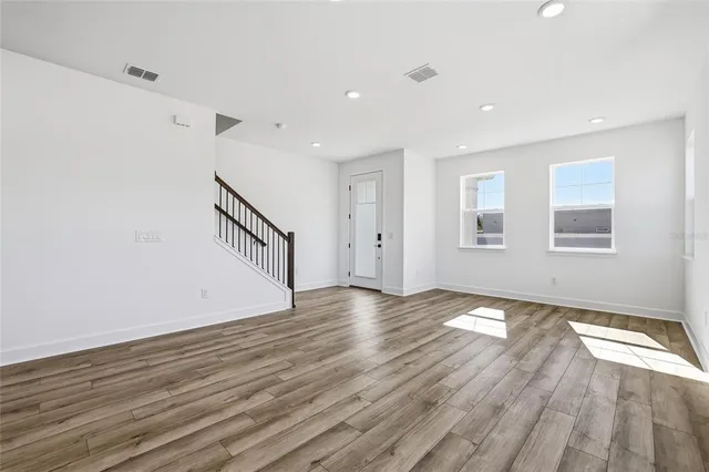 a view of an empty room with wooden floor and window