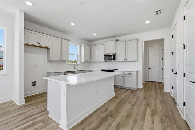 a kitchen with white cabinets stove and sink