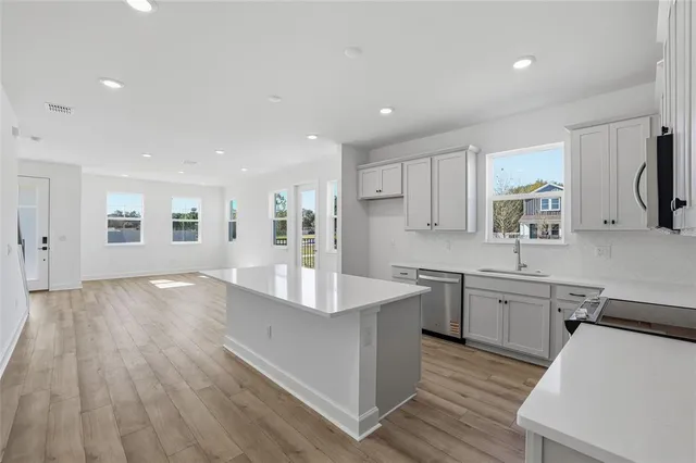 a large kitchen with stainless steel appliances granite countertop a lot of counter space and wooden floors