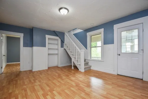 a view of an empty room with wooden floor and stairs