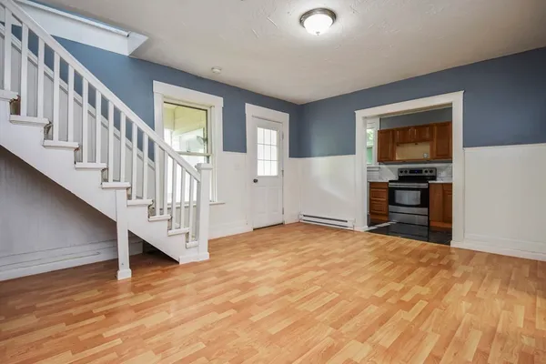 a view of an empty room with wooden floor and stairs