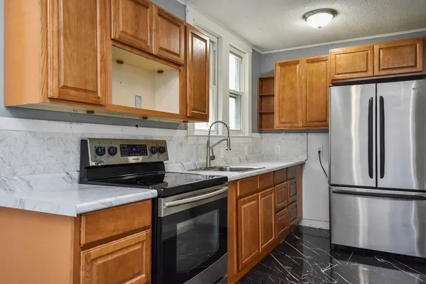 a kitchen with stainless steel appliances granite countertop a refrigerator a stove and a sink with wooden cabinets