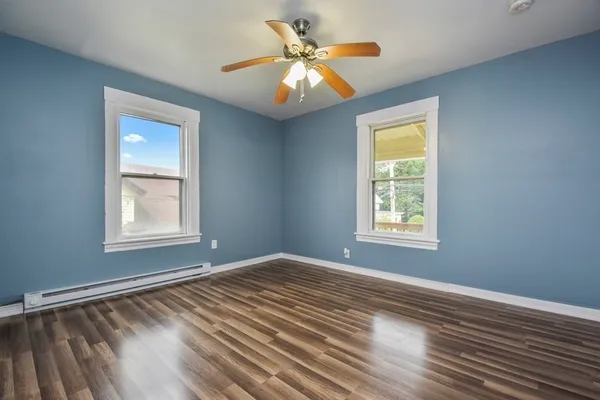 a view of an empty room with window and wooden floor