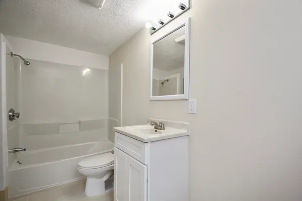 a bathroom with a granite countertop sink a toilet and shower
