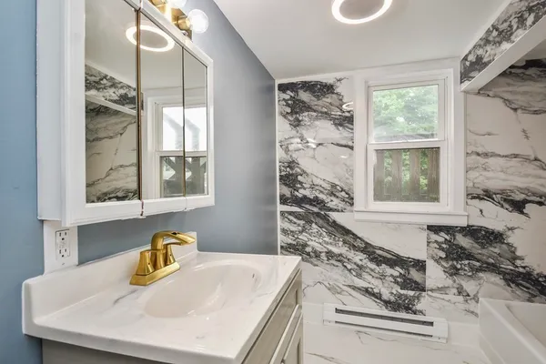 a bathroom with a granite countertop sink and a window