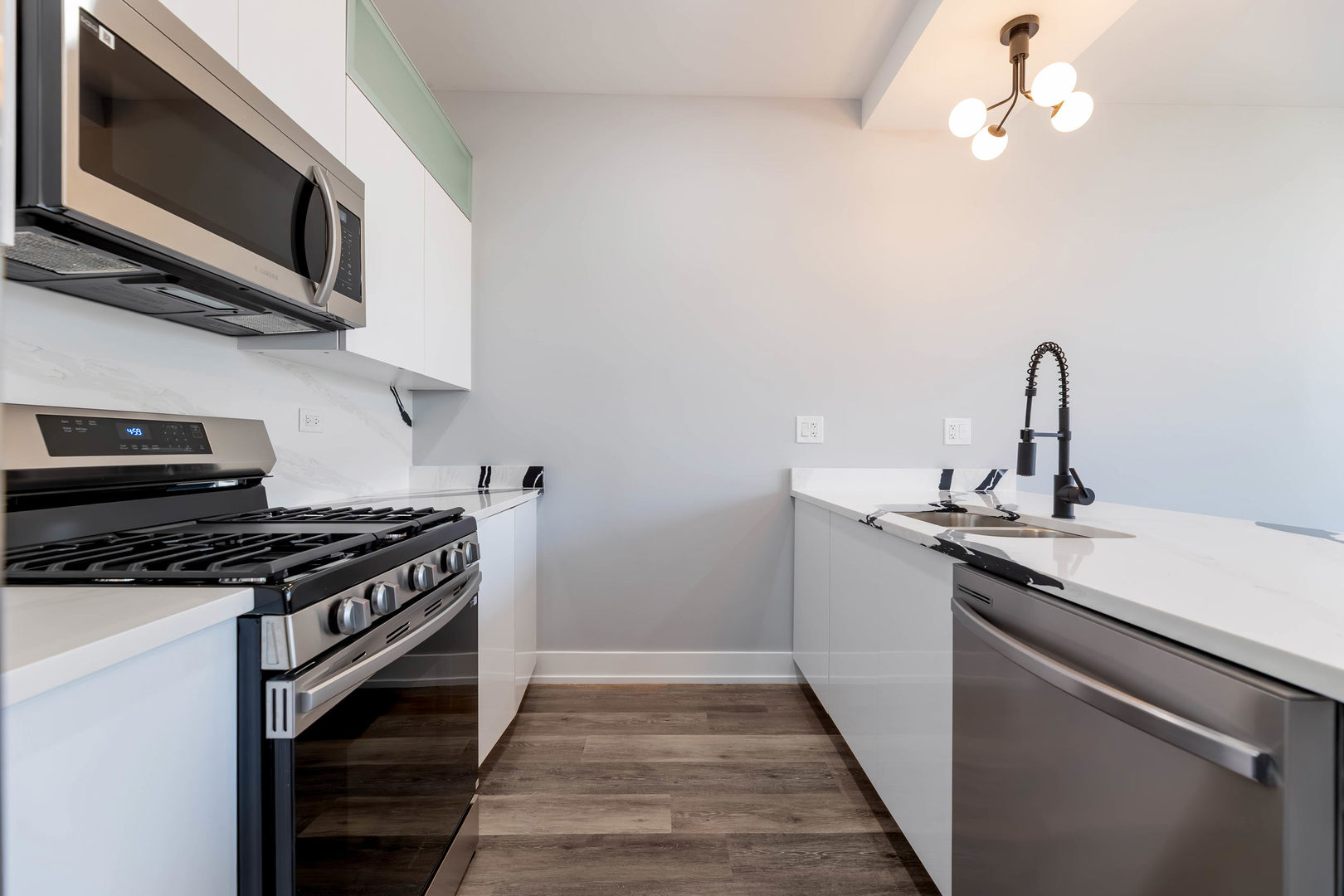 5809 South Indiana Avenue, Unit 2 Chicago, IL 60637 - Photo 5 of 18 a kitchen with stainless steel appliances a sink dishwasher stove and microwave with wooden floor