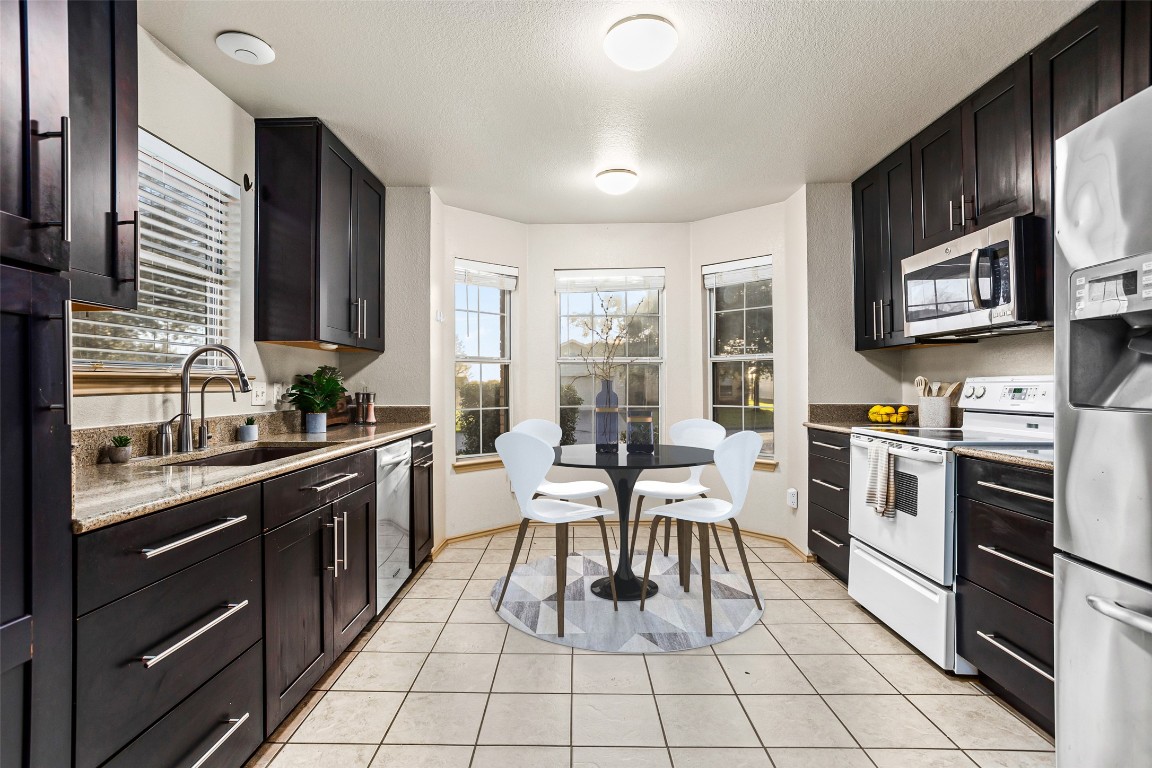 409 Lydia Lane Thrall, TX 76578 - Photo 15 of 39 a kitchen with stainless steel appliances granite countertop a stove top oven a sink dishwasher a dining table and chairs with wooden floor