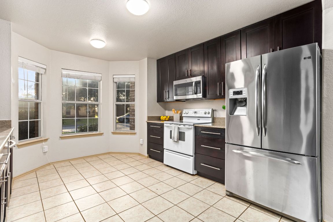 409 Lydia Lane Thrall, TX 76578 - Photo 19 of 39 a kitchen with granite countertop stainless steel appliances a refrigerator sink and microwave
