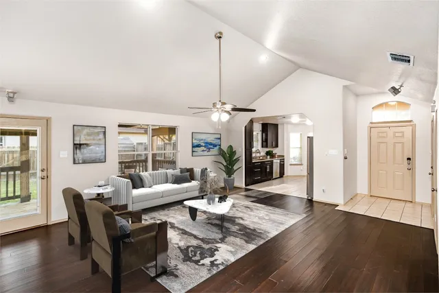 a view of a big room with wooden floor chandelier and windows