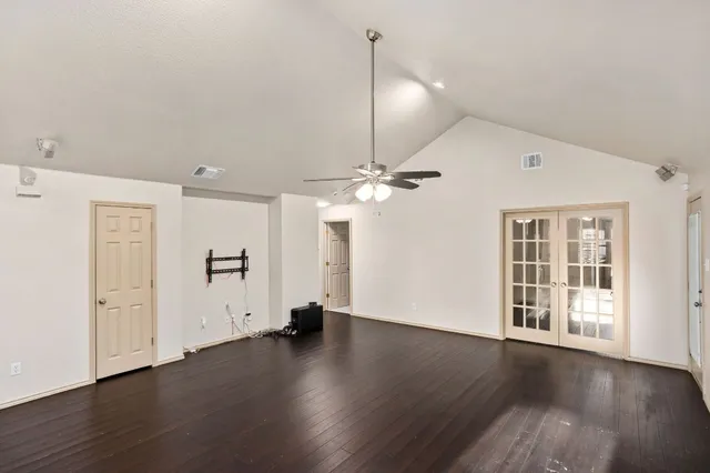 a view of an empty room with wooden floor and a ceiling fan