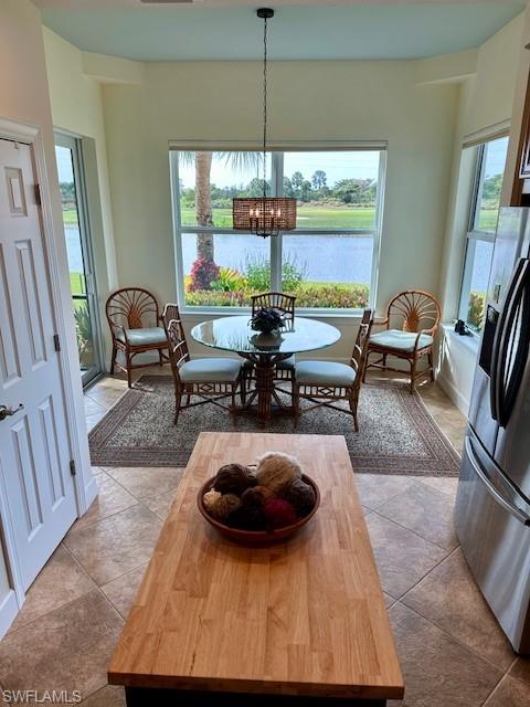 9221 Quartz Lane, Unit 9102 Naples, FL 34120 - Photo 14 of 19 Dining room featuring a notable chandelier, a water view, and light tile patterned floors