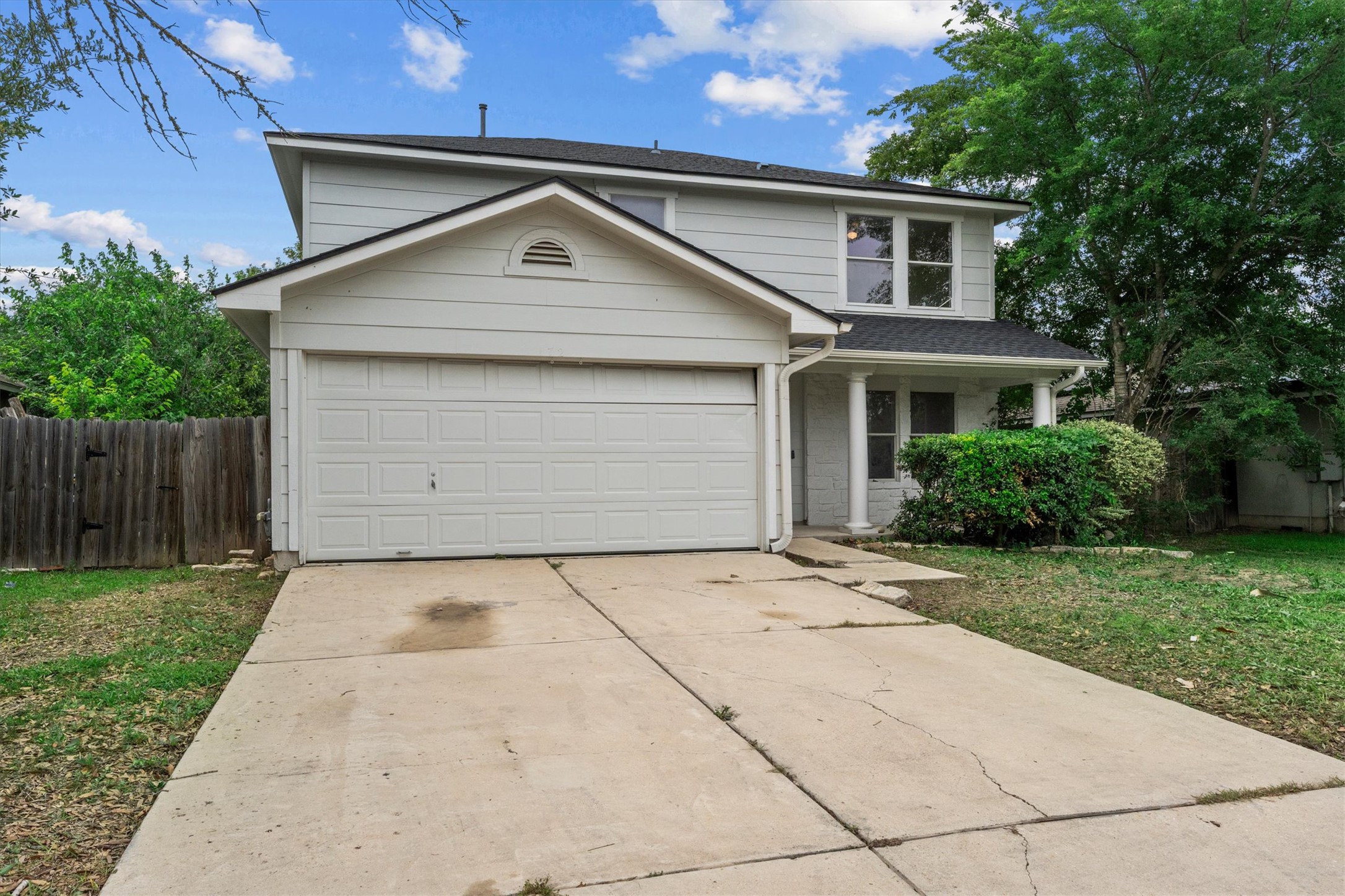 Two-story home with a spacious driveway, attached garage, and mature trees adding to the curb appeal.
