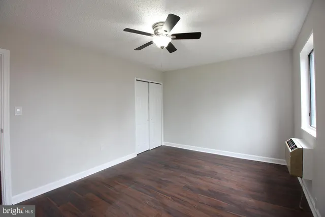 an empty room with wooden floor and ceiling fan