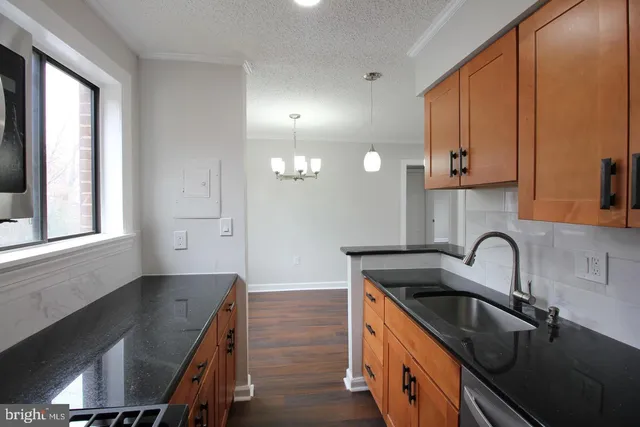 a kitchen with granite countertop a sink a stove and cabinets