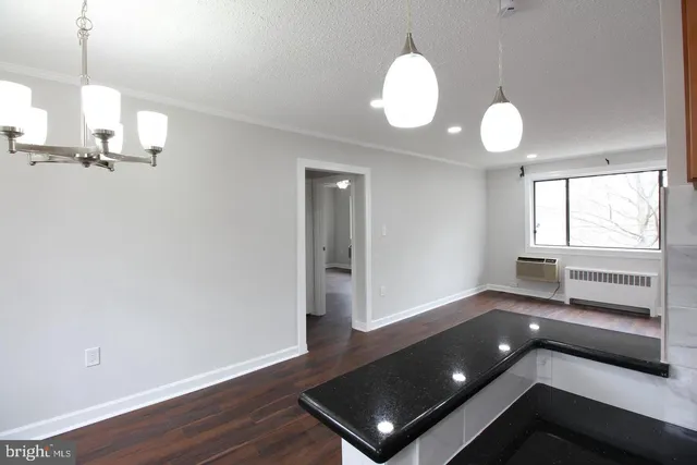 a view of an empty room with wooden floor and window