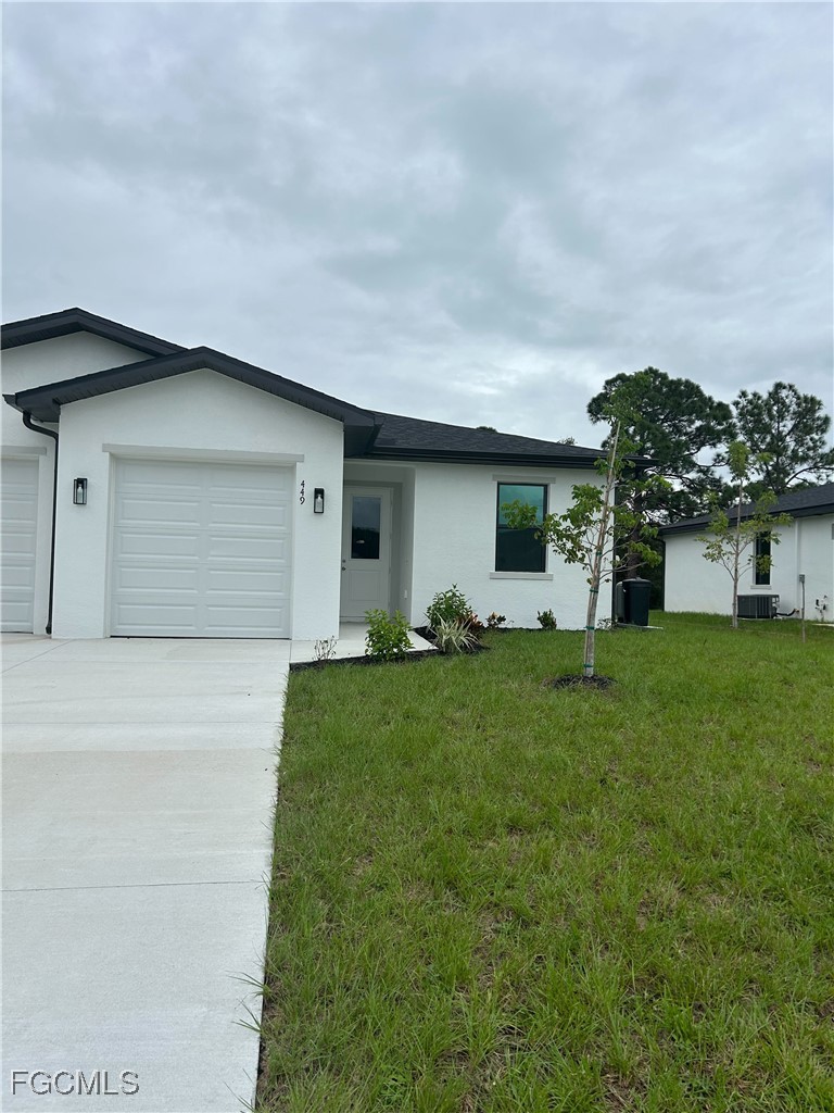 449 Bell Boulevard Lehigh Acres, FL 33974 - Photo 1 of 21 a front view of a house with a yard and garage