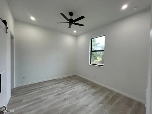an empty room with wooden floor ceiling fan and windows