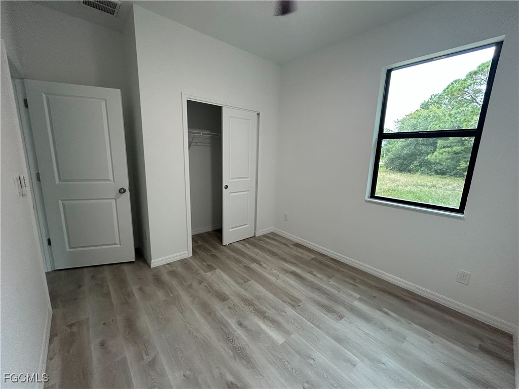 449 Bell Boulevard Lehigh Acres, FL 33974 - Photo 10 of 21 an empty room with wooden floor and windows