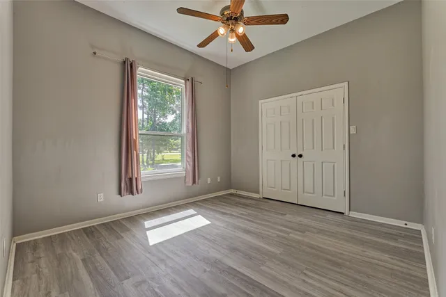 an empty room with windows and fan