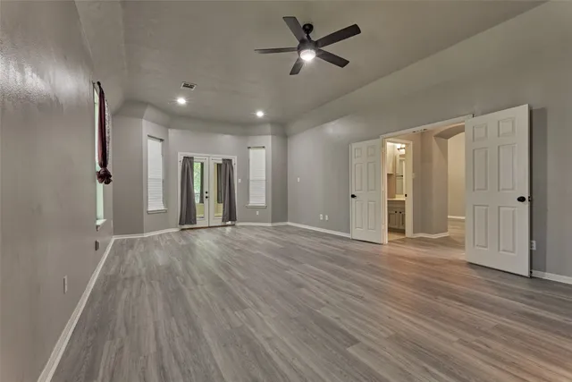 a view of empty room with wooden floor and fan